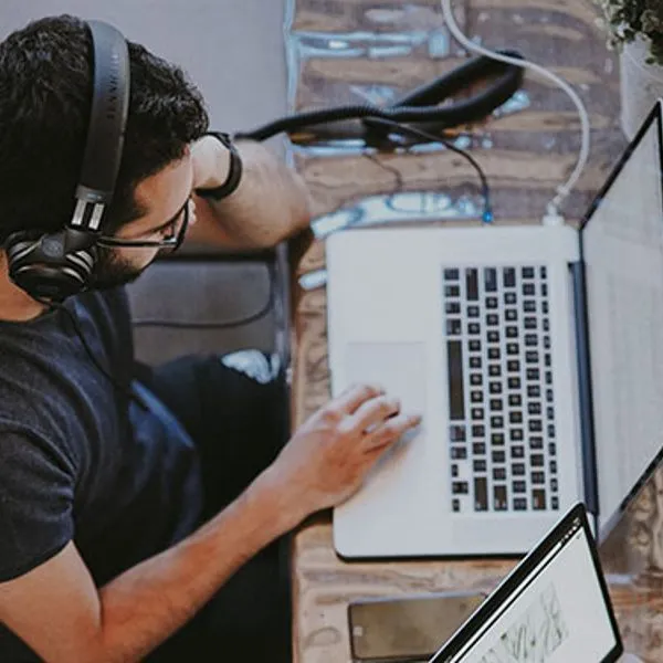 Een man met een headset die op een laptop werkt, van bovenaf gezien