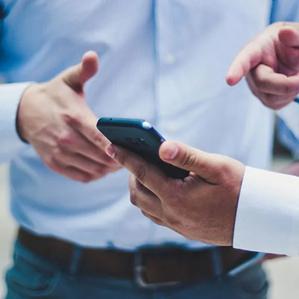 Twee mensen in hemd die samen naar een smartphone kijken